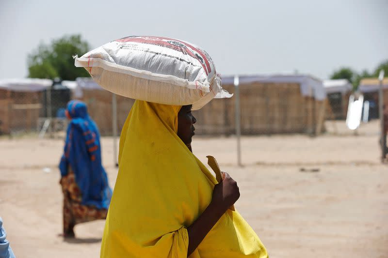 FILE PHOTO: A woman carries a bag of rice during a food rationing at an internally displaced persons (IDP) camp on the outskirts of Maiduguri, northeast Nigeria