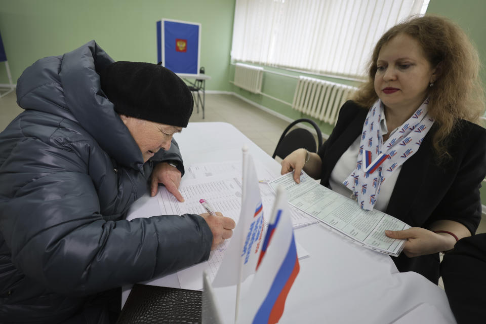 A woman gets a ballot at a polling station during a presidential election in Makiivka, Russian-controlled Donetsk region, eastern Ukraine, Friday, March 15, 2024. People in Moscow-controlled Ukrainian regions are voting in Russia's presidential election, which is all but certain to extend President Vladimir Putin's rule after he clamped down on dissent. (AP Photo)