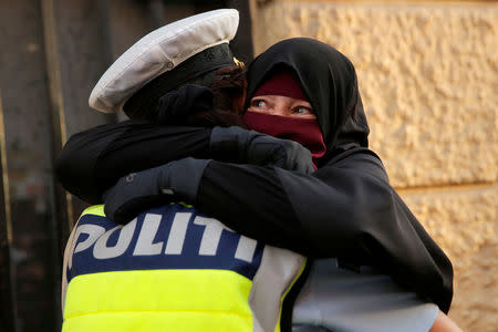 Ayah, 37, a wearer of the niqab weeps as she is embraced by a police officer during a demonstration against the Danish face veil ban in Copenhagen, Denmark, August 1, 2018. REUTERS/Andrew Kelly