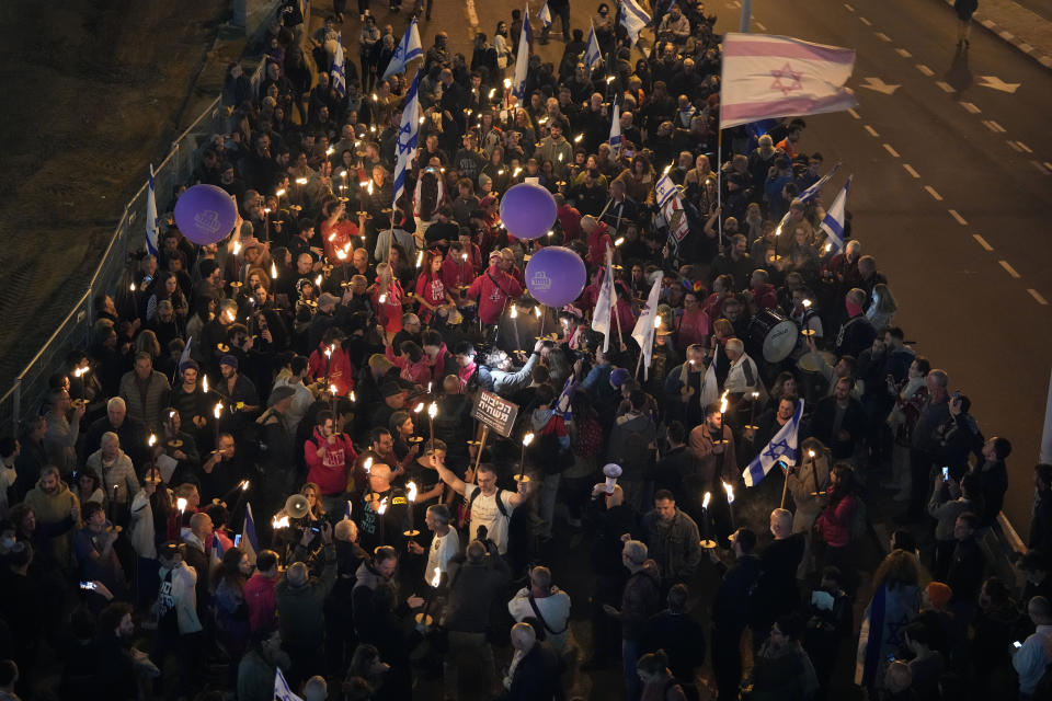 Israelis carry torches at a protest against Israeli Prime Minister Benjamin Netanyahu and his his far-right government that his opponents say threaten democracy and freedoms, in Tel Aviv, Israel, Saturday, Jan. 21, 2023. (AP Photo/ Tsafrir Abayov)