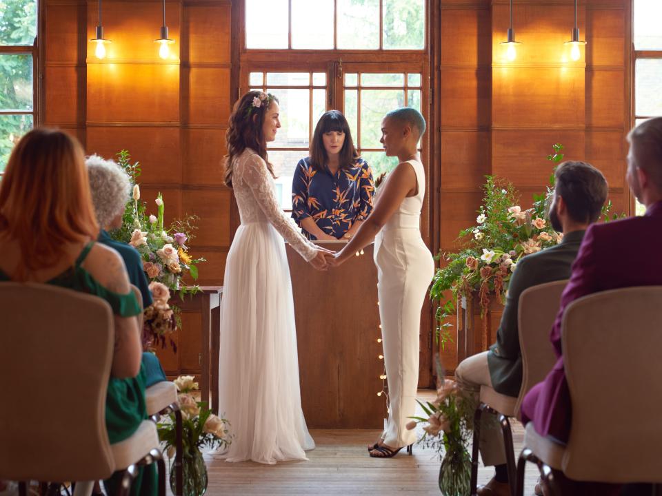 couple getting married in venue with orange-y wood finishes