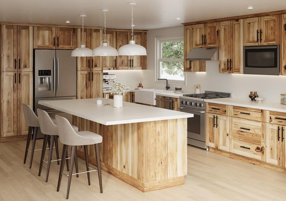 Kitchen with an island, natural pine-look wood cabinet, and white pendant lighting.