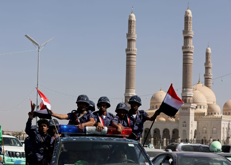 Houthi police troopers ride on the back of a patrol truck in Sanaa