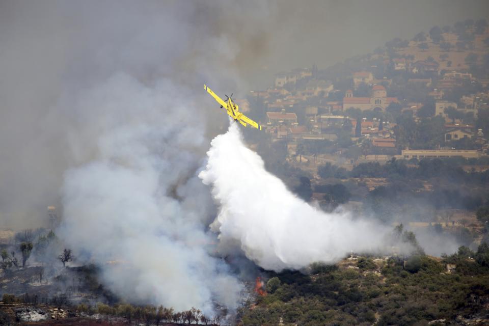 An aircraft drops water over a fire in Apesia semi-mountainous village near Limassol, southwestern Cyprus, Monday, Aug. 7, 2023. Greece on Monday dispatched two Canadair fire-fighting aircraft after a call for assistance from fellow European Union member Cyprus to help fight a blaze that has scorched miles of mountainous terrain. (AP Photo/Philippos Christou)