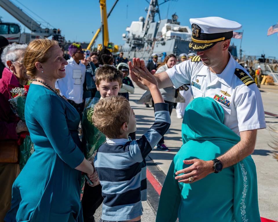 U.S. Navy Cmdr. James Diefenderfer Jr. gets a high-five from his son for Wednesday's homecoming of the USS The Sullivans at Naval Station Mayport.