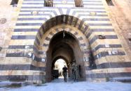 Syrian government soldiers walk through the entrance to the Khan al-Wazir market in Aleppo on September 16, 2016