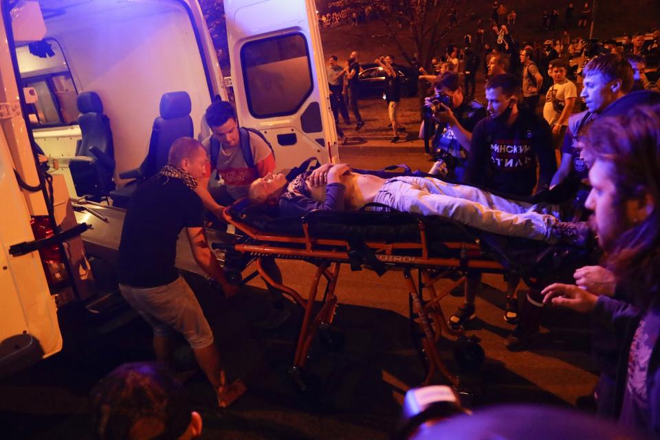 Protesters help paramedics to carry a wounded person into an ambulance after clashes with police in Minsk, Belarus, Sunday, Aug. 9, 2020. Police and protesters clashed in Belarus' capital and the major city of Brest on Sunday after the presidential election in which the authoritarian leader who has ruled for a quarter-century sought a sixth term in office. (AP Photo/Sergei Grits)
