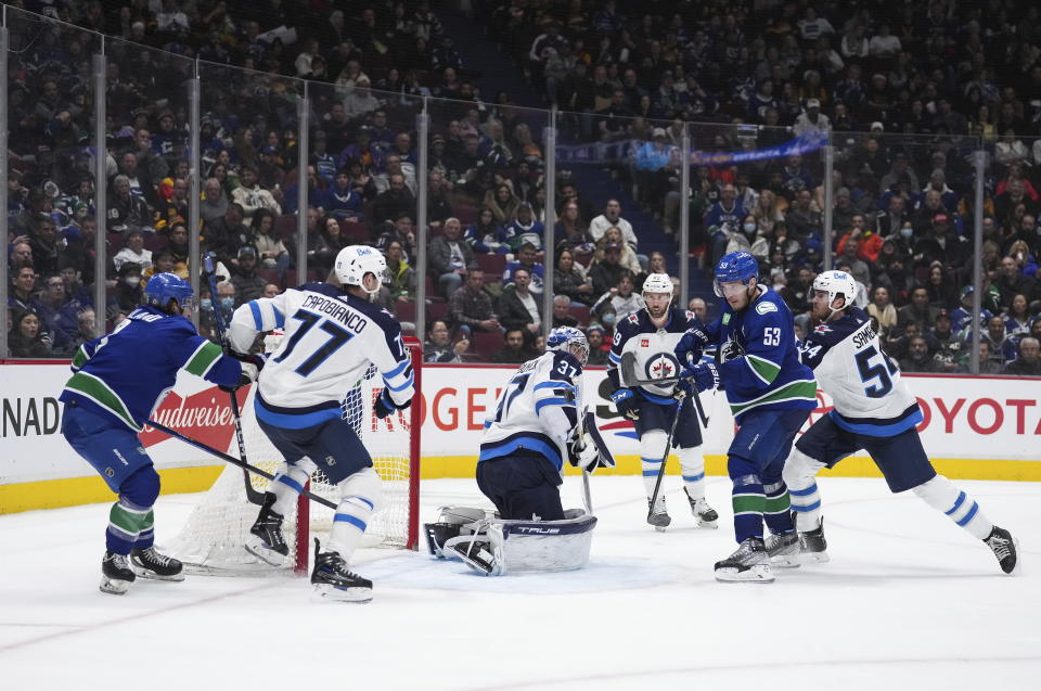 Winnipeg Jets goalie Connor Hellebuyck (37) makes the save as Vancouver Canucks' Bo Horvat (53) watches the rebound during the third period of an NHL hockey game, Saturday, Dec. 17, 2022 in Vancouver, British Columbia. (Darryl Dyck/The Canadian Press via AP)