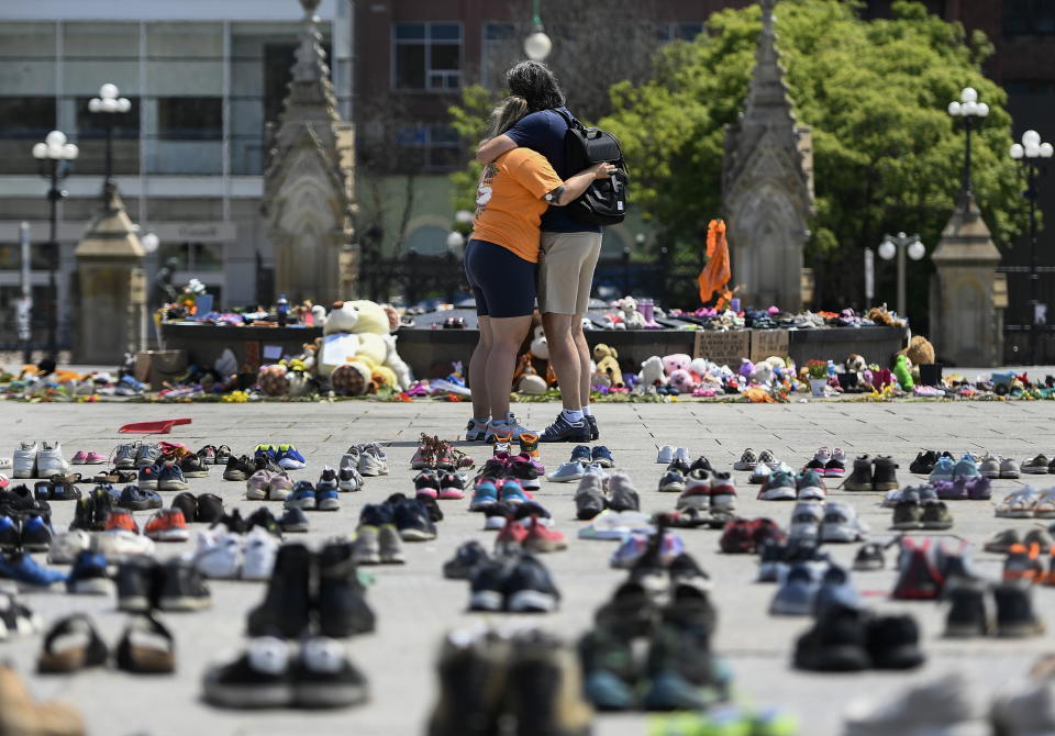 People embrace in front of the Centennial Flame on Parliament Hill at a memorial for the 215 children whose remains were found at the grounds of the former Kamloops Indian Residential School at Tk'emlups te Secwépemc First Nation in Kamloops, B.C., in Ottawa on Friday, June 4, 2021. (Justin Tang/The Canadian Press via AP)