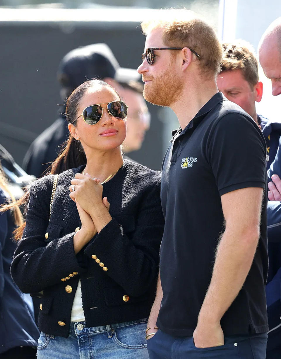 Meghan Markle with her hands clasp together as she looks up at Prince Harry