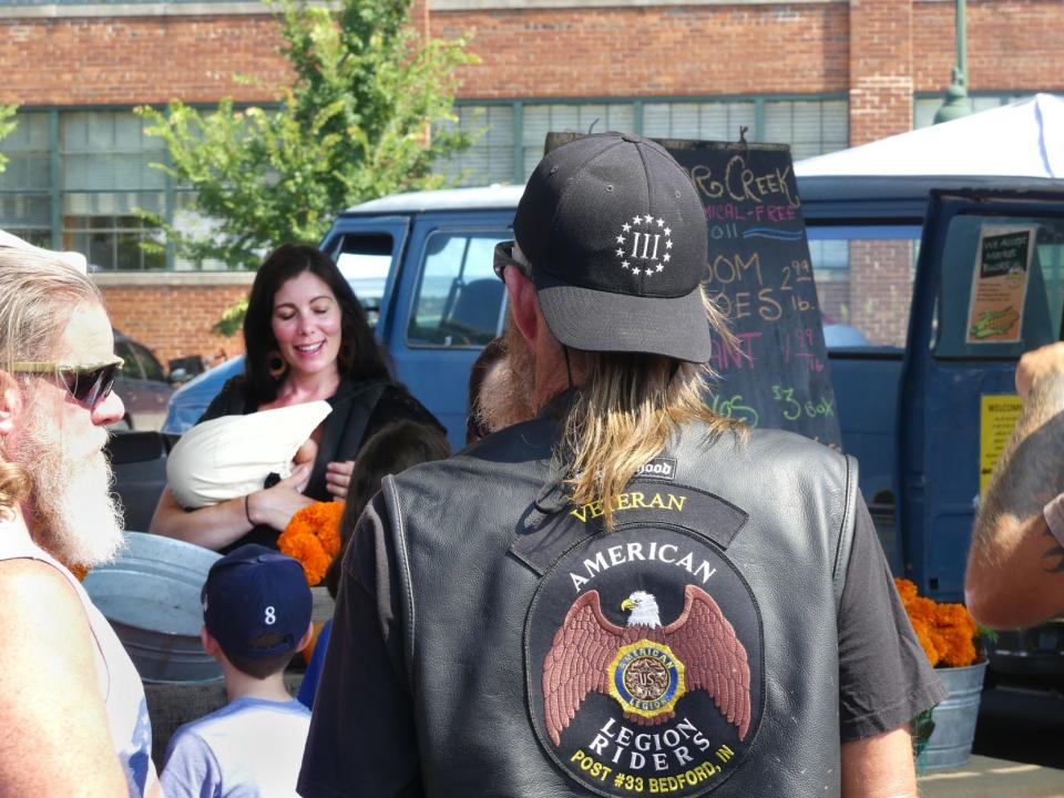 A counter-protester approaches Sarah Dye, left center, at the Bloomington Community Farmers’ Market July 27, 2019, after Bloomington police arrested a woman carrying a sign alleging Schooner Creek Farm’s association with a white nationalist hate group.