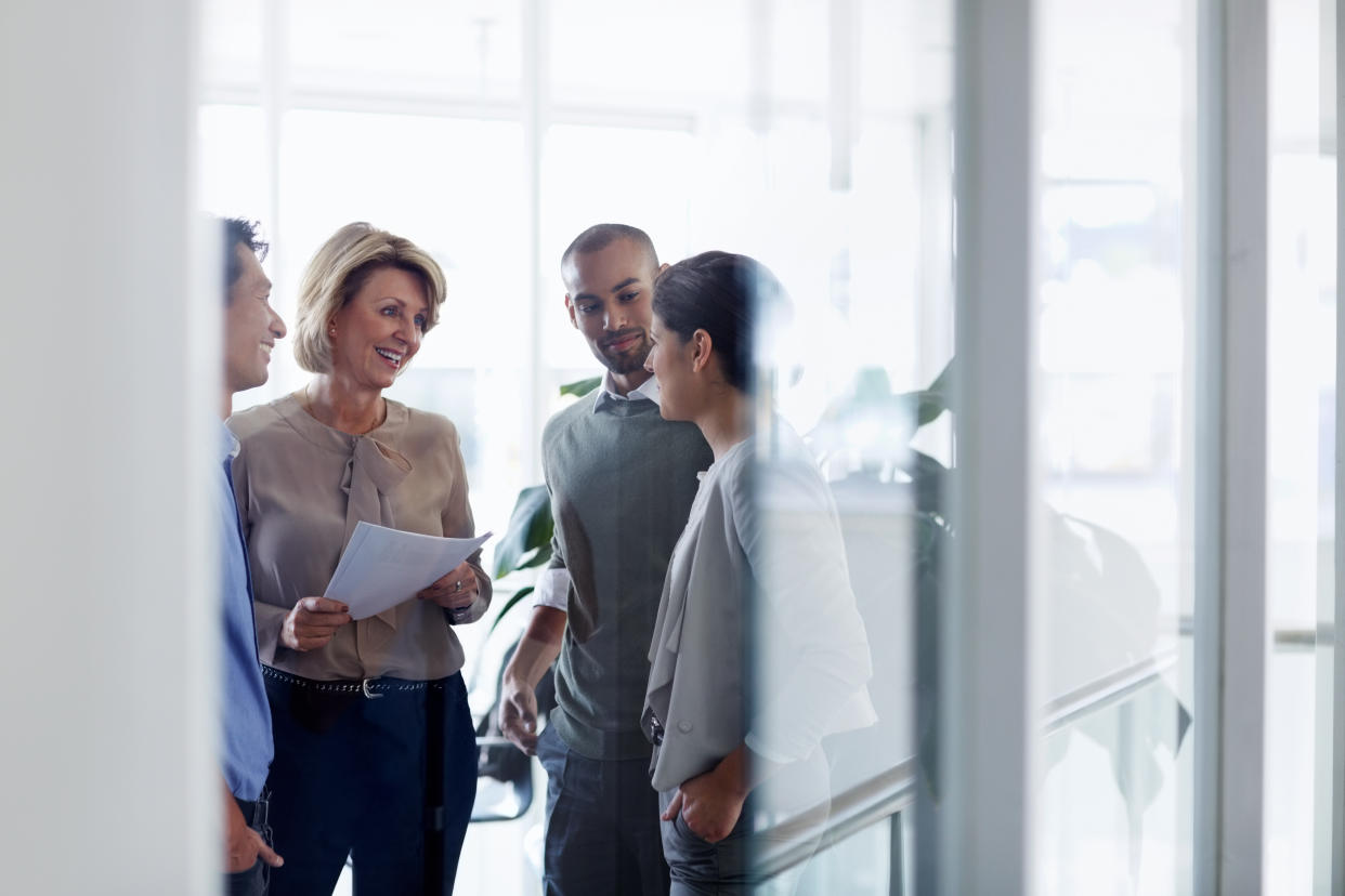 Smiling businesswoman discussing over document with colleagues in office