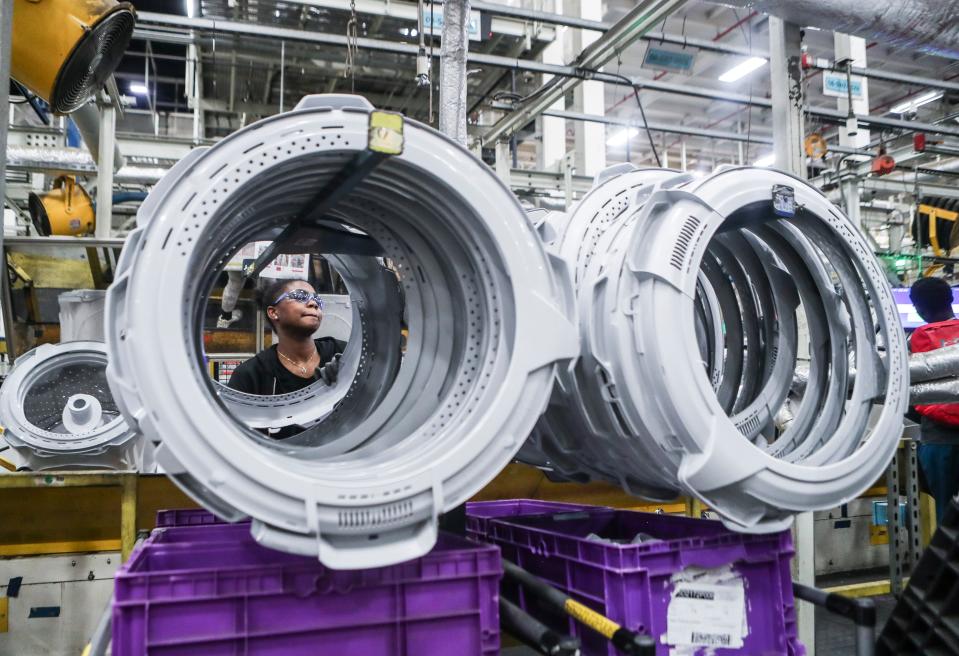 GE worker Celes Fears is framed among a group of plastic rings that will be installed on the new GE 4.5 cubic ft. Capacity washing machines featuring a Spanish-language control panel move along an assembly line towards packaging on April 15, 2024 at GE's Appliance Park in Louisville, Ky. GE is looking to capitalize on the the growing Spanish-speaking market in the U.S.