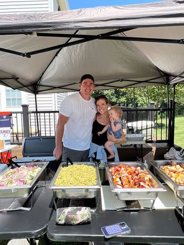 <p>Courtesy of Rachael Sullivan</p> Rachael Sullivan and Tom Sullivan with their daughter serving meals to college students.