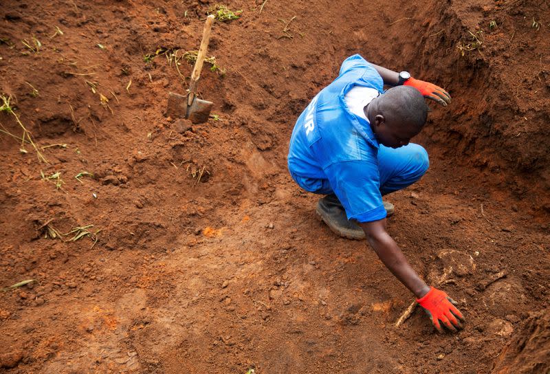 A Burundian worker from the Truth and Reconciliation Commission extracts a body of an unidentified person from a mass grave in the Bukirasazi hill in Karusi Province