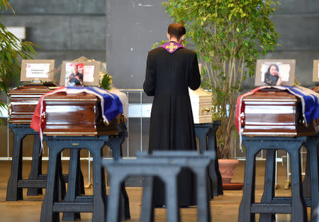 A priest stands next to coffins containing bodies of victims of the Genoa bridge collapse at the Genoa Trade Fair and Exhibition Centre in Genoa, Italy August 17, 2018. REUTERS/Massimo Pinca