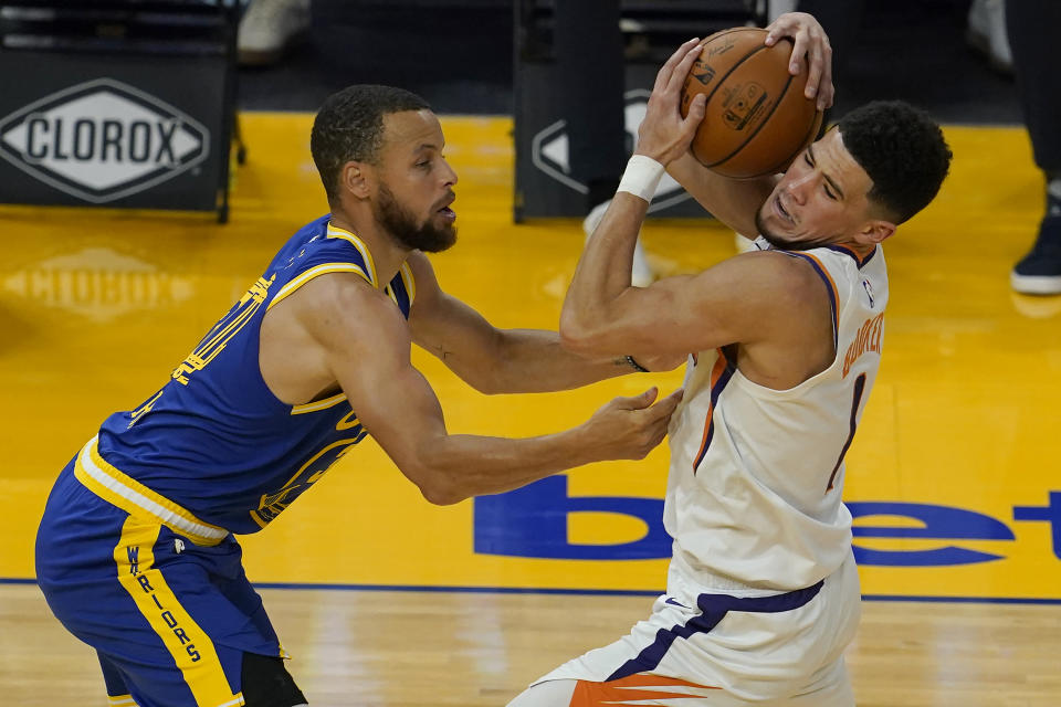 Phoenix Suns guard Devin Booker, right, is defended by Golden State Warriors guard Stephen Curry during the first half of an NBA basketball game in San Francisco, Tuesday, May 11, 2021. (AP Photo/Jeff Chiu)