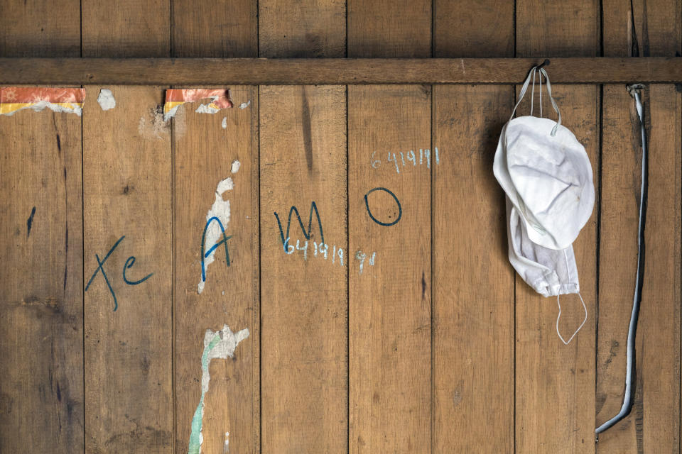 In this April 5, 2020 photo, protective face coverings belonging to Raul Coyantes hang from a nail inside the small room he rents in a deteriorating building nicknamed “Luriganchito” after the country’s most populous prison, in Lima, Peru To try to address the coming humanitarian disaster, Peru has begun distributing about $400 million to feed 12 million poor people for one month. But the money doesn't seem to be reaching most of the families at Luriganchito . (AP Photo/Rodrigo Abd)