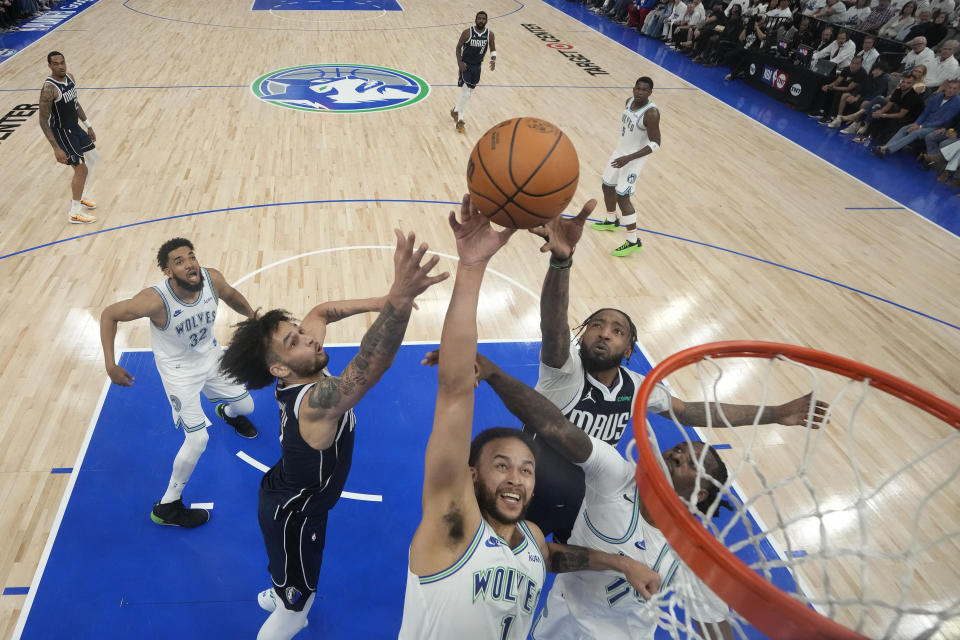 Minnesota Timberwolves forward Kyle Anderson (1) reaches for a rebound against Dallas Mavericks center Dereck Lively II, left, and forward Derrick Jones Jr., back, right, during the first half of Game 1 of the NBA basketball Western Conference finals Wednesday, May 22, 2024, in Minneapolis. (AP Photo/Abbie Parr)