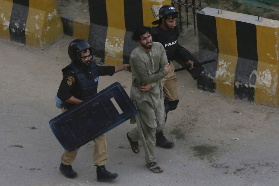 Police officers detain a supporter of former Pakistani Prime Minister Imran Khan's party, 'Pakistan Tehreek-e-Insaf' during a protest to condemn a shooting incident on their leader's convoy, in Karachi, Pakistan, Friday, Nov. 4, 2022. Khan who narrowly escaped an assassination attempt on his life the previous day when a gunman fired multiple shots and wounded him in the leg during a protest rally is listed in stable condition after undergoing surgery at a hospital, a senior leader from his party said Friday. (AP Photo/Fareed Khan)