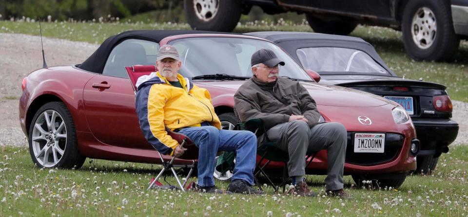 A pair of Mazda enthusiasts watch action zoom around during the SVRA Vintage Festival Weekend, Saturday, May 15, 2021, at Elkhart Lake's Road America near Plymouth, Wis.