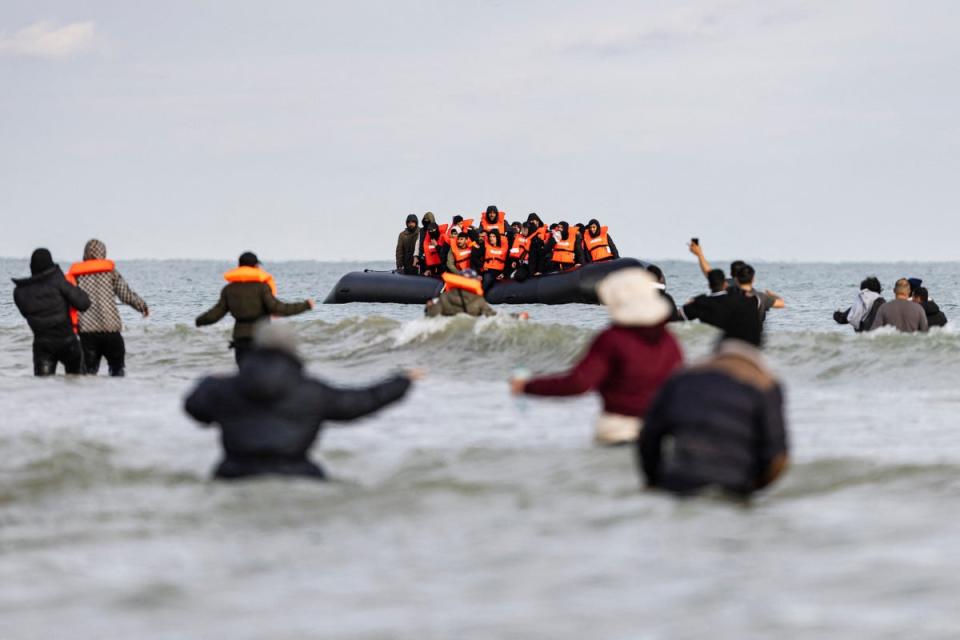 Migrants wave to a smuggler's boat in an attempt to cross the English Channel, on the beach of Gravelines, near Dunkirk (AFP via Getty Images)
