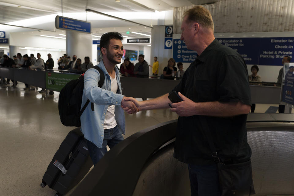 Michael White, a Navy veteran who was jailed in Iran for several years on spying charges, right, shakes hands with Michael's former fellow prisoner and Iranian political activist Mahdi Vatankhah at the Los Angeles International Airport in Los Angeles, Thursday, June 1, 2023. Vatankhah, while in custody and after his release, helped White by providing White's mother with crucial, firsthand accounts about her son's status in prison and by passing along letters White had written while he was locked up. Once freed, White did not forget. He pushed successfully this year for Vatankhah's admission to the United States, allowing the men to be reunited last spring, something neither could have envisioned when they first met in prison years earlier. (AP Photo/Jae C. Hong)