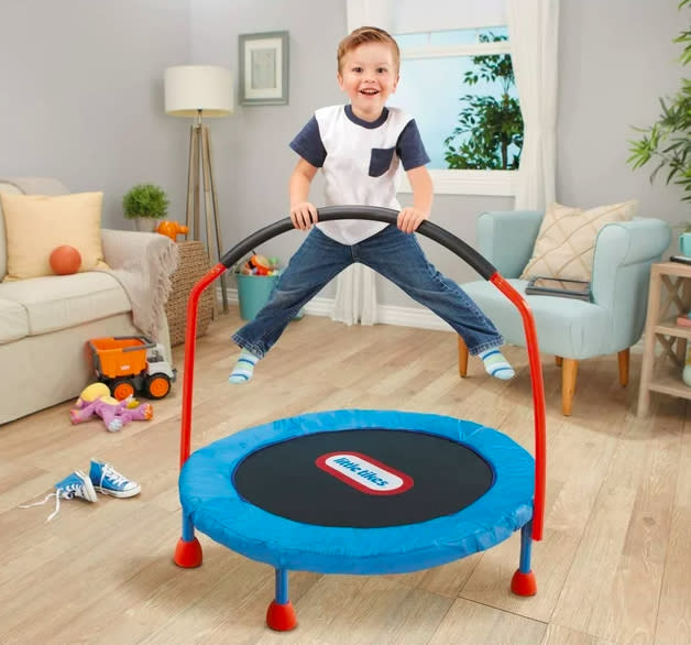 A boy jumping on the trampoline in a living room