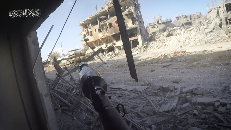 In this image from video released by Hamas on Dec. 2, 2023, a Hamas fighter aims an Al-Yasin 105 rocket at an Israeli tank in Beit Hanoun, Gaza. Cobbled together by militants in Gaza, the rockets are a copy of the Russian-made PG-7VR, which features a tandem warhead specifically designed to defeat reactive-armor systems like that used on Israeli tanks. Watermark at upper left reads “military media.” (Hamas via AP)
