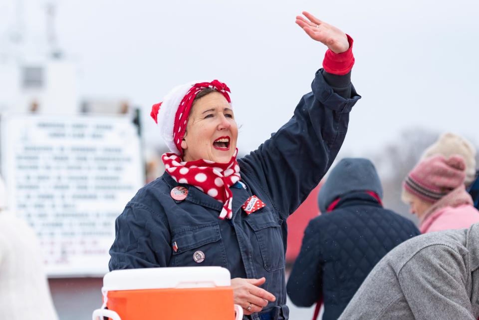 Angie Morthland, vice president of the American Rosie the Riveter Association Cheboygan and Emmet chapter, waves as she distributes cookies and hot chocolate to visitors attending the U.S. Coast Guard's send-off party for the Cutter Mackinaw at the Cheboygan County Marina on Sunday, Nov. 26, 2023.