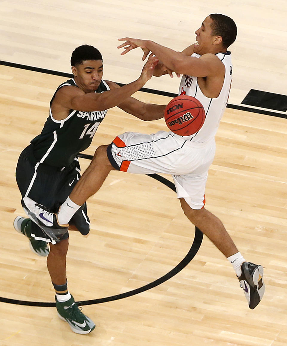 Virginia guard Malcolm Brogdon, right, is fouled by Michigan State guard Gary Harris during second half in a regional semifinal at the NCAA men's college basketball tournament, Friday, March 28, 2014, in New York. (AP Photo/Julio Cortez)