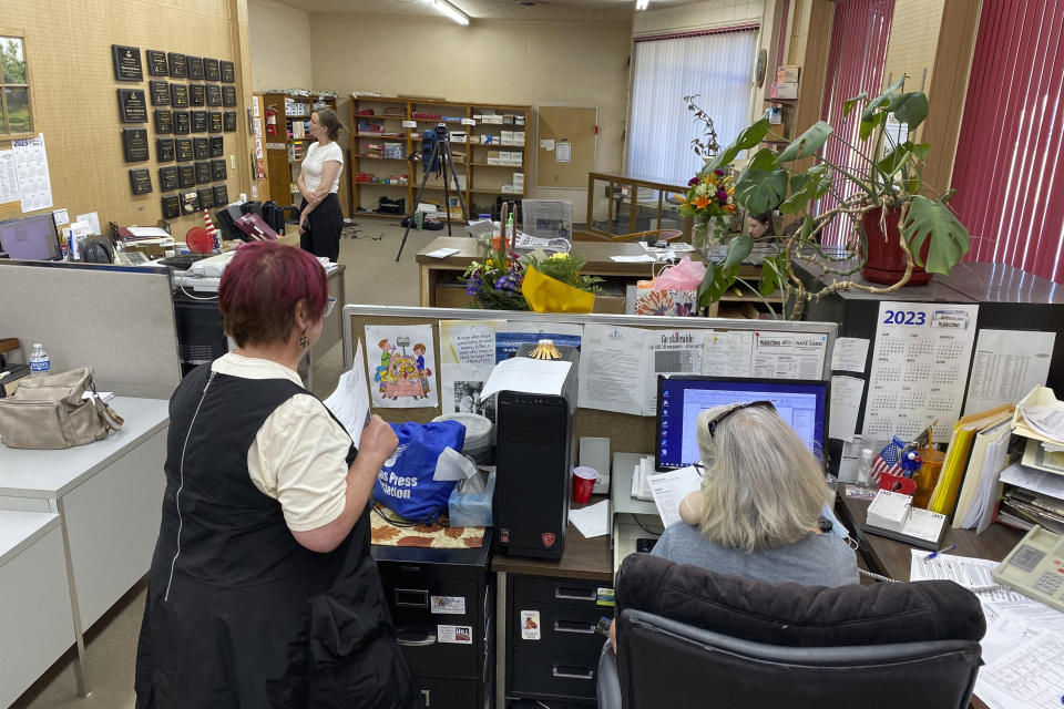 Marion County Record reporters Deb Gruver, left foreground, and Phyllis Zorn work at their computers while Katherine Jacobsen of the Committee to Protect Journalists stands in the background on Tuesday, Aug. 15, 2023, in Marion County, Kansas. The staff of the weekly newspaper was able to put out a new edition for Wednesday despite a police seizure of most of its computers and other equipment. (Emily Bradbury/Kansas Press Association via AP)