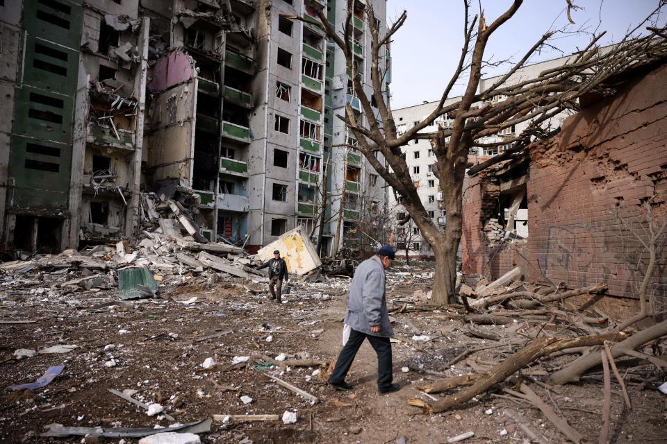 Men walk past a residential building damaged by Russian shelling in the city of Chernihiv, Ukraine, March 4, 2022. / Credit: DIMITAR DILKOFF/AFP/Getty