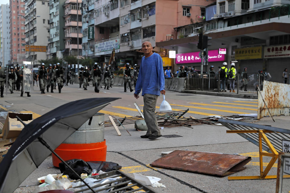 A man walks across a barrier as riot police patrol on a road in Hong Kong, Saturday, Oct. 12, 2019. The protests that started in June over a now-shelved extradition bill have since snowballed into an anti-China campaign amid anger over what many view as Beijing's interference in Hong Kong's autonomy that was granted when the former British colony returned to Chinese rule in 1997. (AP Photo/Kin Cheung)