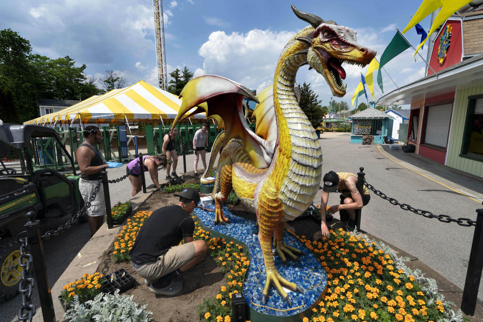 Workers at the Funtown amusement park plant flowers ahead of opening day, Wednesday, May 26, 2021, in Saco, Maine. The park plans to operate only five days a week due to a worker shortage. (AP Photo/Robert F. Bukaty)