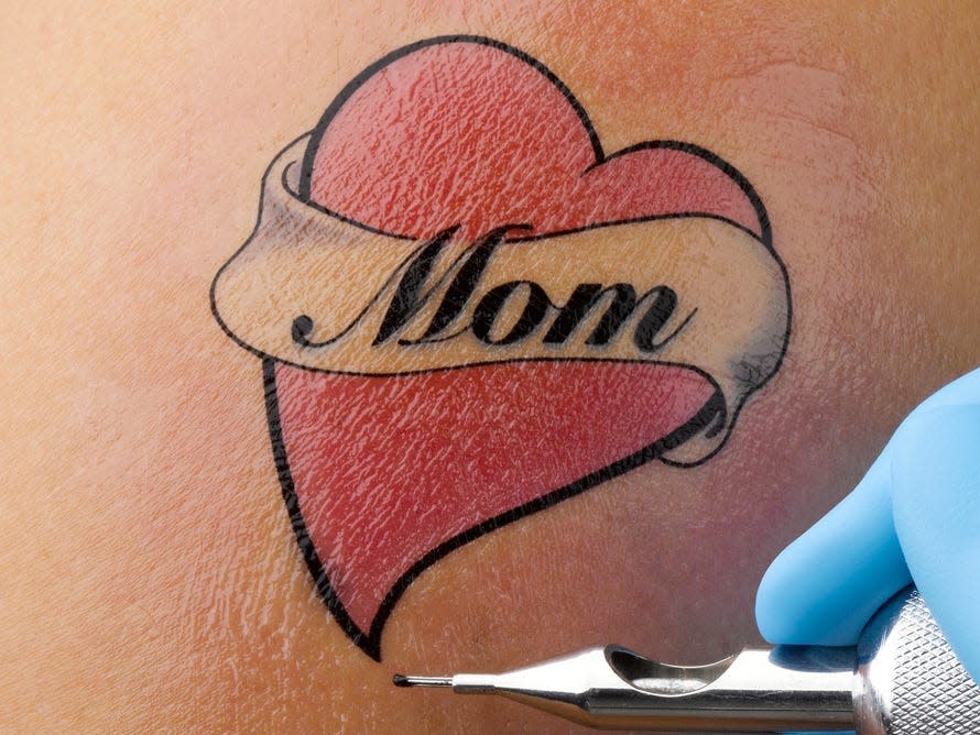 Finished red tattoo heart with "Mom" text on person's shoulder