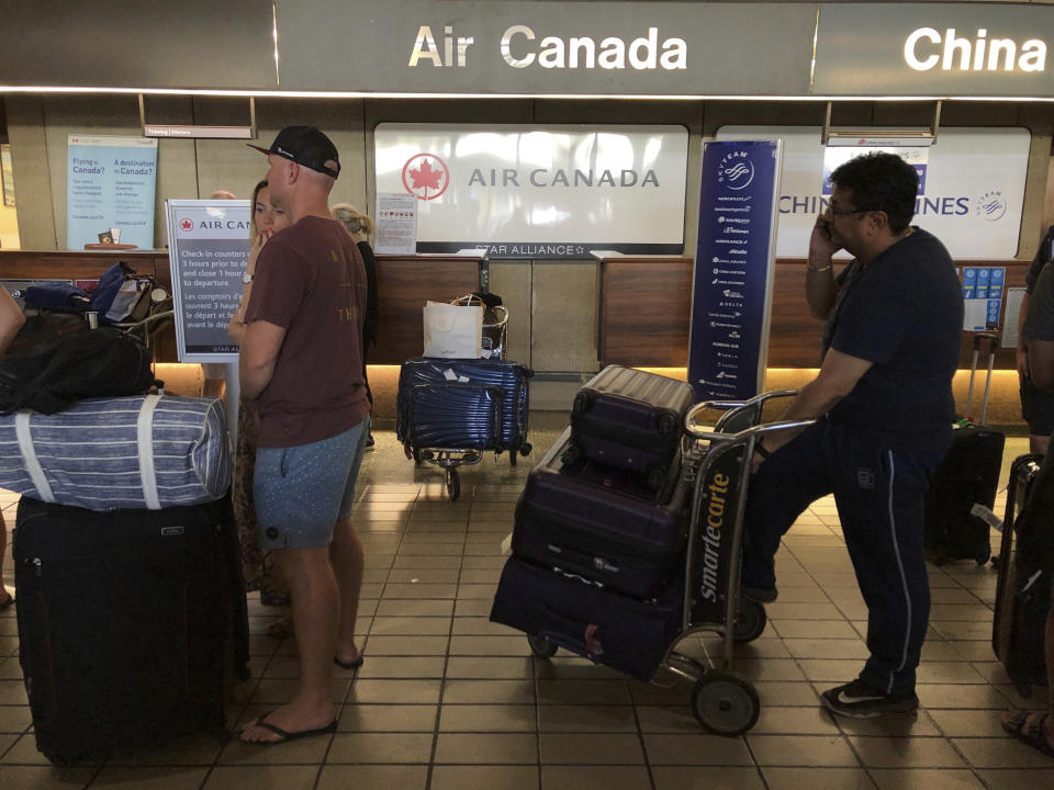 Passengers from an Australia-bound Air Canada flight diverted to Honolulu Thursday, July 11, 2019, after about 35 people were injured during turbulence, stand in line at the Air Canada counter at Daniel K. Inouye International Airport to rebook flights. Air Canada said the flight from Vancouver to Sydney encountered "un-forecasted and sudden turbulence," about two hours past Hawaii when the plane diverted to Honolulu. (AP Photo/Caleb Jones)