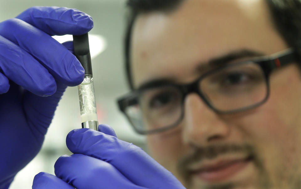 FILE - In this July 19, 2019, file photo, Pierce Prozy examines a Yolo! brand vape oil cartridge marketed as a CBD product at Flora Research Laboratories in Grants Pass, Ore. Janell Thompson, a pioneer in marketing CBD as a health product, has pleaded guilty to selling large quantities of synthetic marijuana which was secretly added to vapes, sickening dozens. Prosecutors has also tied Thompson to Yolo!, which sickened at least 33 people in Utah. (AP Photo/Ted Warren, File)