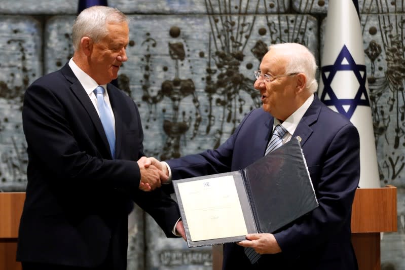 Israeli President Reuven Rivlin gives Benny Gantz, leader of Blue and White party, a file during a nomination ceremony at the President's residency in Jerusalem