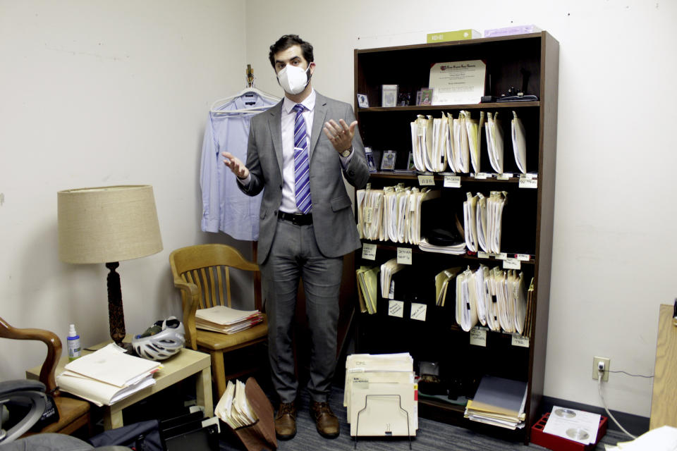 Public defender Drew Flood with the nonprofit law firm Metropolitan Public Defender looks his files for the criminal cases he is currently working on in this May 5, 2022 photo in Portland, Ore. Flood, who was hired eight months ago by the firm, is carrying 100 cases and says he sometimes has so many cases he can't remember details such as what is in the client's police report or what plea deal is being offered. A post-pandemic glut of delayed cases has exposed shocking constitutional landmines impacting defendants and crime victims alike in Oregon, where an acute shortage of public defenders has even led judges to dismiss serious cases. (AP Photo/Gillian Flaccus)