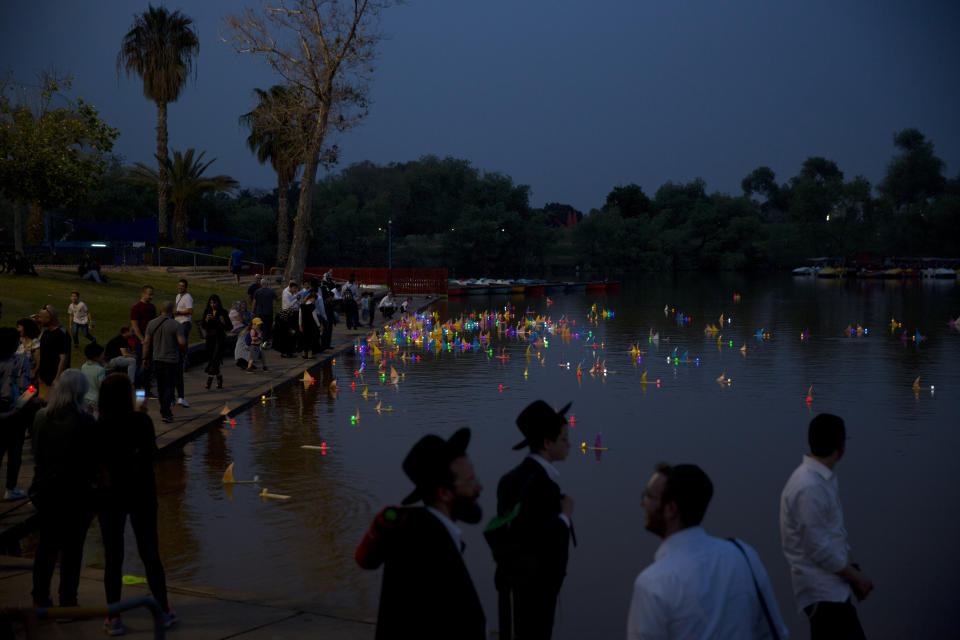 People look on floating handmade boats with the names of Nazi concentration camps, during a ceremony marking the annual Holocaust Remembrance Day in Hayarkon park in Tel Aviv, Israel, Wednesday, May 1, 2019. Israel marking the annual Day of Remembrance for the six million Jewish victims of the Nazi genocide who perished during World War II. Hebrew reads "to remember". (AP Photo/Oded Balilty)