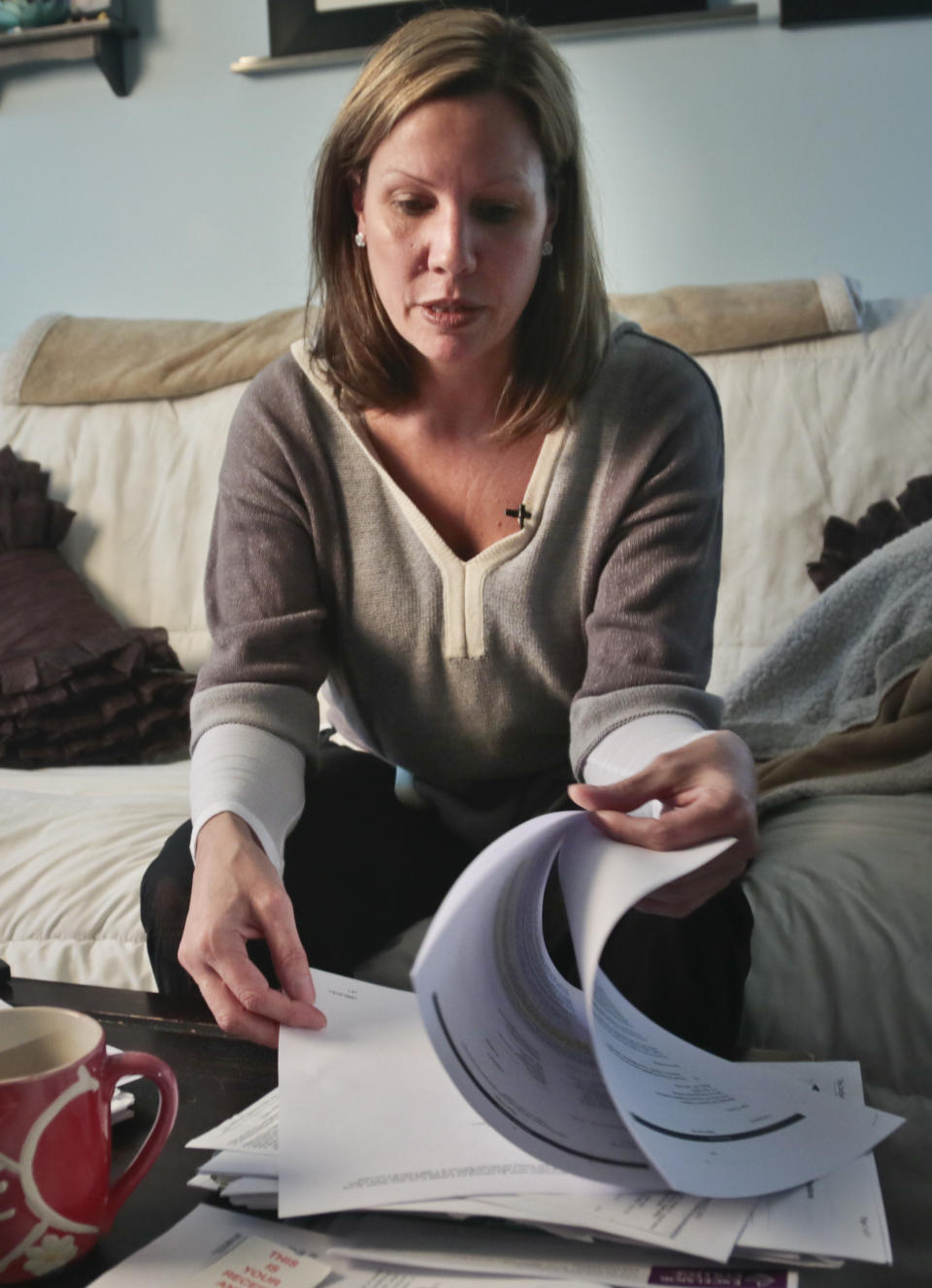 In this March 11, 2014 photo, Nora Milligan looks through a pile of legal healthcare documents at her home in Patchogue, NY. Milligan, a single mom, is fighting healthcare providers in court for denial of care to her heroin-addicted son. Having exhausted her finances for his care, she continues to live in the home she raised him even as it is being foreclosed. As the number of heroin users in the U.S. rises, more addicts are seeking help but running into barriers that block them from treatment, including lack of beds in packed facilities, high costs for care and unwillingness on the part of insurance companies to pay for inpatient rehab. (AP Photo/Bebeto Matthews)