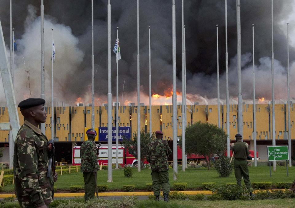 FILE - In this Wednesday, Aug. 7, 2013 file photo, police stand guard as fire engulfs the international arrivals unit of the Jomo Kenyatta International Airport, in Nairobi, Kenya. Putting that disaster in the past , Kenya Airways’ chief executive Titus Naikuni is predicting an exciting couple of years for African air travel, with new Boeing Dreamliners, the opening of a new terminal and, on the horizon, Kenya's first direct flights to the United States.(AP Photo/Sayyid Azim, File)
