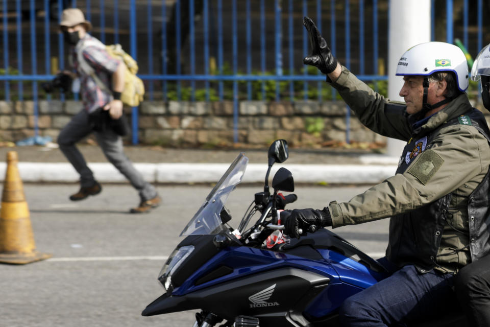 Brazil's President Jair Bolsonaro, waves as he leads a caravan of motorcycle enthusiasts following him through the streets of the city, in a show of support for Bolsonaro, in Sao Paulo, Brazil, Saturday, June 12, 2021. (AP Photo/Marcelo Chello)