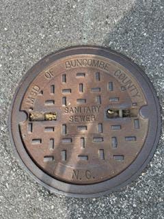 An older manhole cover before the Metropolitan Sewerage District of Buncombe County began to roll out covers with the logo design in 2010.