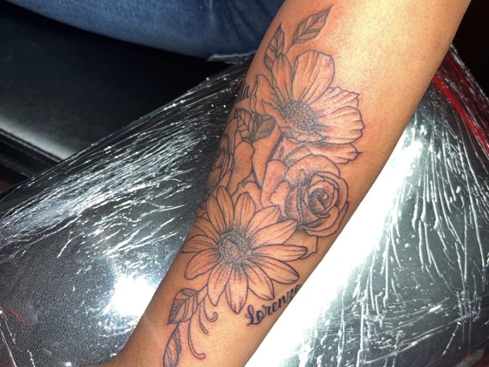Flower tattoos with daisies and roses on a person's arm
