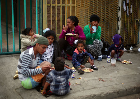 Migrants, part of a caravan of thousands from Central America trying to reach the United States, eat breakfast on the roadside outside of a temporary shelter in Tijuana, Mexico, November 28, 2018. REUTERS/Hannah McKay