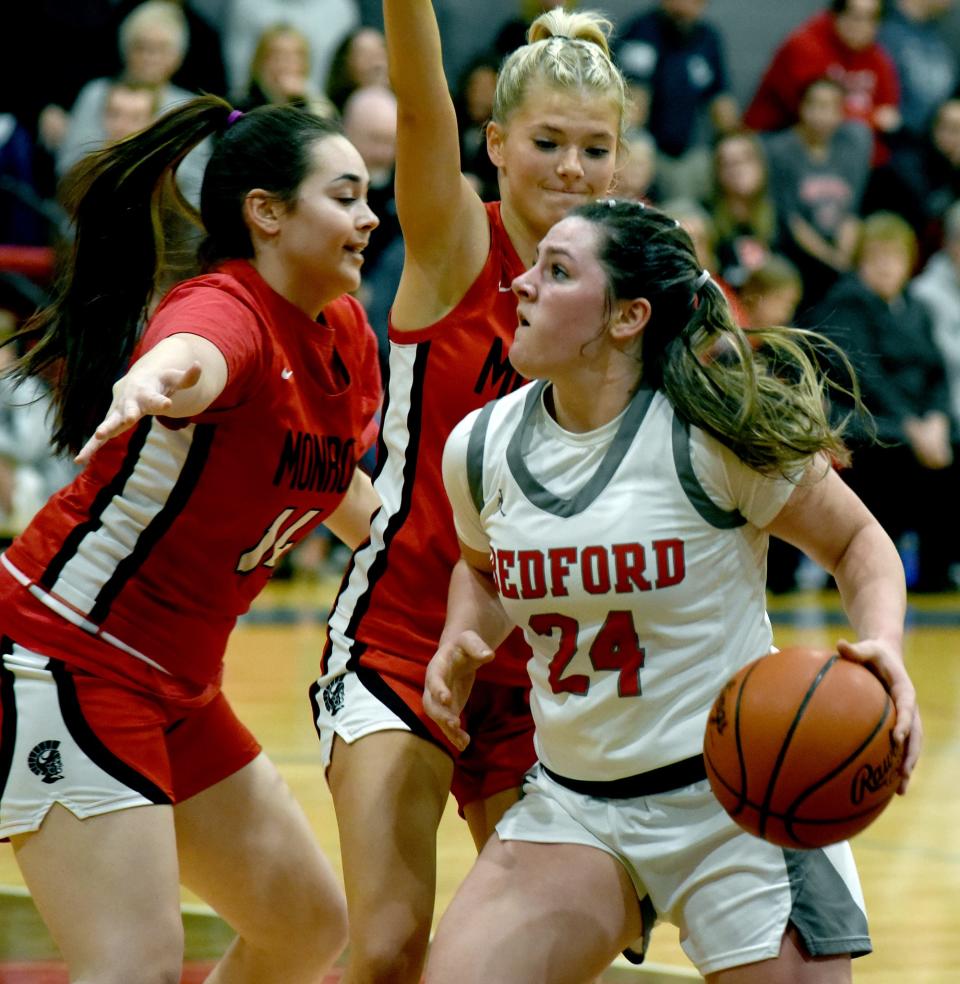 Peyton Behnke of Bedford is double teamed by Taylor Ray and Molly Meier of Monroe Friday night. Bedford won 50-20.