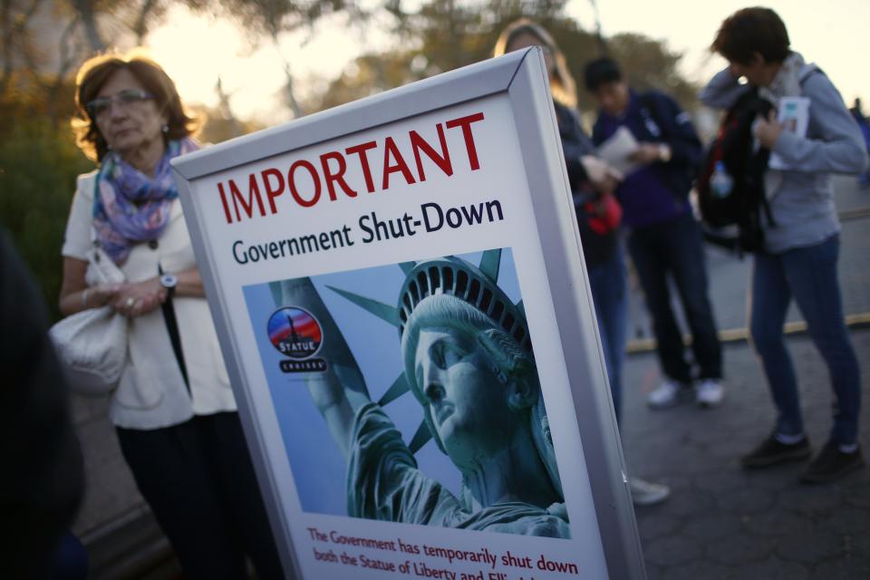 Tourists stand next to a sign announcing the closure of the Statue of Liberty, a U.S. National Park, due to the U.S. Government shutdown near the ferry dock to the Statue of Liberty in Battery Park in New York, October 1, 2013. The U.S. government began a partial shutdown on Tuesday for the first time in 17 years, potentially putting up to 1 million workers on unpaid leave, closing national parks and stalling medical research projects. REUTERS/Mike Segar (UNITED STATES - Tags: POLITICS BUSINESS TRAVEL)