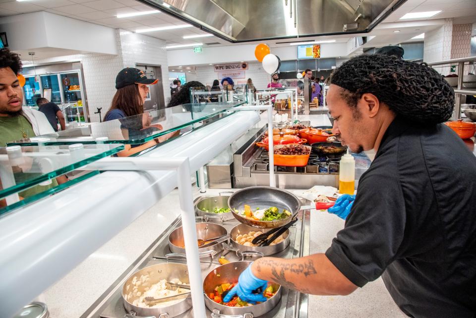 Worker prepares a hot meal for a student at the dining hall.